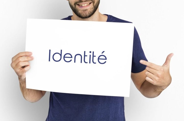 Une personne tient une affiche sur laquelle le mot identité est inscrit et la pointe du doigt