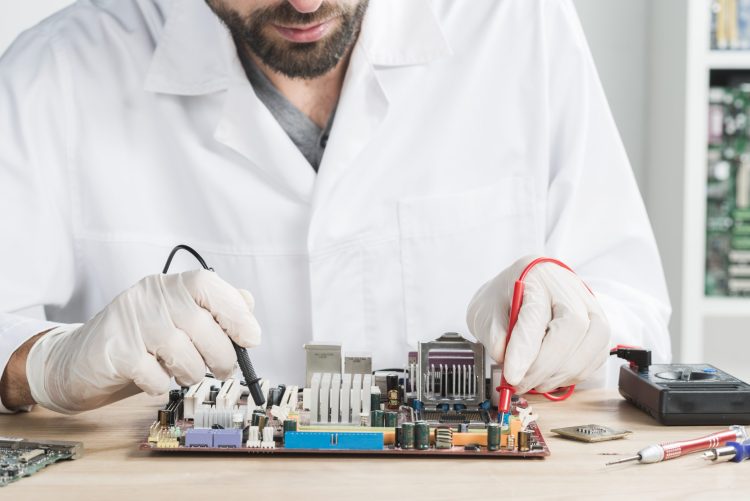 Un technicien recherche un court-circuit avec un multimètre sur une carte mère